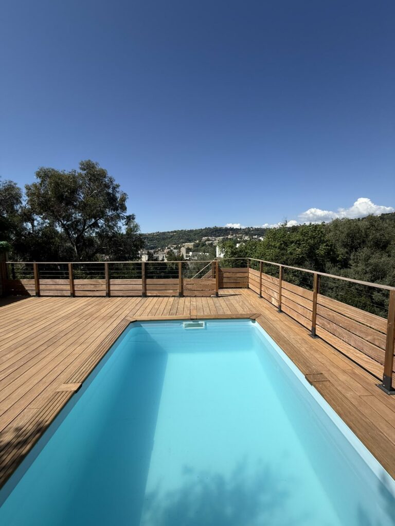 Piscine terminée à Gairaut (Nice) sur terrain en pente avec terrasse bois et vue panoramique — réalisation Genesius GCR